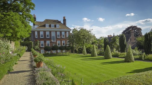 The brickwork exterior of Fenton House, London, in the sun, with manicured garden in front